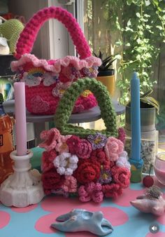 a table topped with lots of colorful crocheted bags and candles on top of it