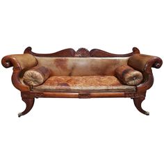 an ornate wooden couch with leather upholstered back and arm rests against a white background