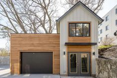 a two story house with wood siding on the side and garage doors open to let in natural light