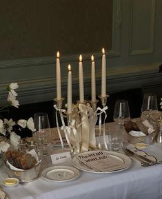 a table is set with white flowers and candles for an elegant dinner or party setting