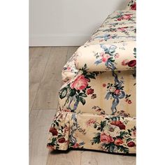 a floral print couch with wooden floors and white walls