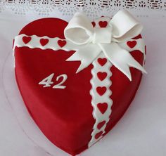 a red heart shaped cake with white ribbon