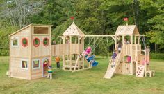 a wooden play set in the middle of a grassy area with children playing on it