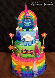 there is a multi layer cake decorated with monsters and rainbows on the bottom tier