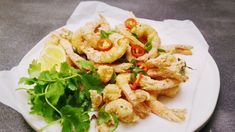 a white plate topped with fried shrimp and veggies next to a lemon wedge