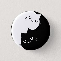 a black and white button with two cats sleeping on it's back, both facing each other