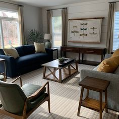 a living room with couches, chairs and tables in front of two large windows