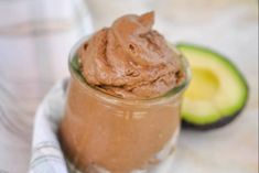 a glass jar filled with chocolate pudding next to an avocado