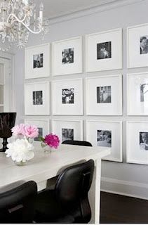 a white dining room table with black chairs and pictures on the wall behind it,