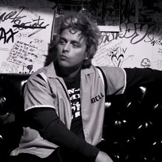 a young man sitting on top of a couch covered in graffiti