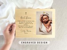 a hand holding up a wooden photo frame with a baby's name on it