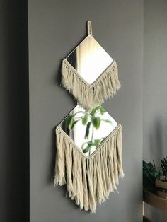 two mirrors mounted to the side of a wall with tassels hanging from them