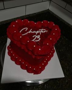 a heart shaped cake with the number 23 on it sitting on a counter next to a tile wall