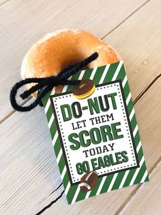 a donut that is sitting on top of a wooden table next to a tag with the words do not let them score today