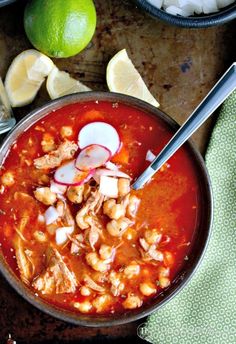 a bowl of chicken and bean soup with limes on the side next to it