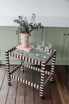 a glass table with wine glasses and a potted plant sitting on top of it