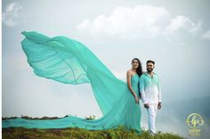 a man and woman standing on top of a grass covered hill next to each other