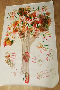 a tree made out of handprints on a piece of white paper with red, orange and green paint