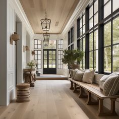 a long hallway with wooden floors and large windows on either side of the entry door