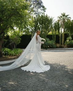 a woman in a wedding dress is posing for the camera with her long veil draped over her head