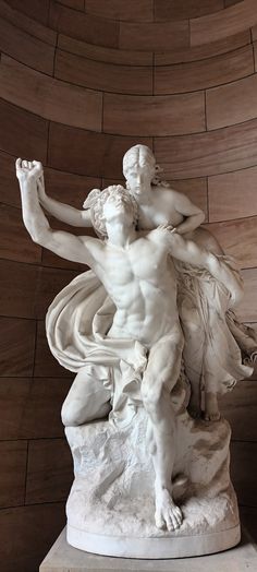 a statue of a man holding a woman on top of a white marble block wall