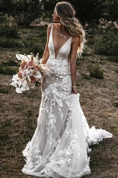 a woman in a white wedding dress holding a bouquet and looking at the back of her dress