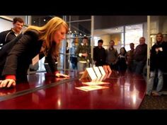 a group of people standing around a table with books on it and one woman leaning over the edge