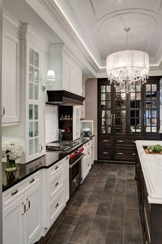 a large kitchen with white cabinets and black counter tops, along with a chandelier hanging from the ceiling