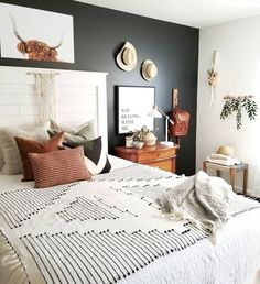 a bed room with a neatly made bed and two hats on the headboards