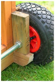 a red wheel is attached to the side of a wooden structure