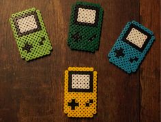 four different colored cell phones made out of perler beads on a wooden table top