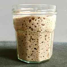 a glass jar filled with food sitting on top of a gray counter next to a white wall