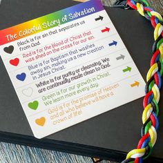 a rainbow - colored bracelet with the bible verse written on it, sitting next to a book