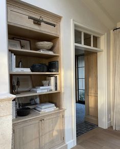 an open bookcase in the corner of a room with a door leading to another room