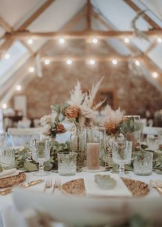 the table is set with flowers, candles and place settings for guests to sit at