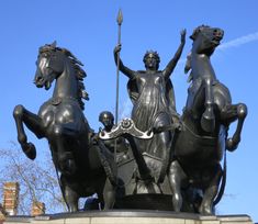 a statue of three horses and a woman holding a spear with two men on them