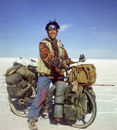 a man standing next to a motorcycle with bags on it's back in the snow