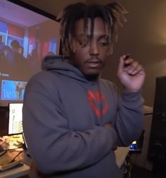 a young man with dreadlocks standing in front of a computer monitor and keyboard