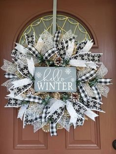 a black and white christmas wreath with the words hello winter on it hanging from a front door