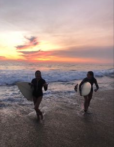 two women walking on the beach with surfboards