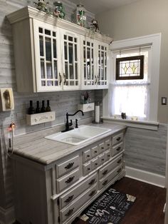 a kitchen with white cabinets and gray counter tops, along with a rug on the floor