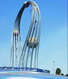 a large metal sculpture on top of a building with two balls hanging from it's sides