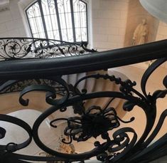 looking down at the spiral staircase in an old building with wrought iron railings and windows