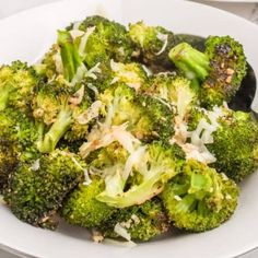 a white plate topped with broccoli covered in cheese