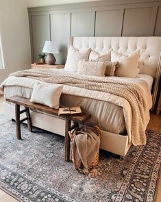 a bedroom with a bed, bench and rug on the floor in front of it