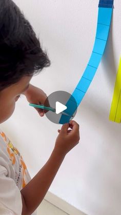 a little boy that is playing with some scissors and tape on the side of a wall