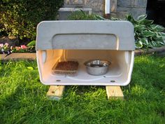 an outdoor oven sitting in the grass with two bowls on it's front and side