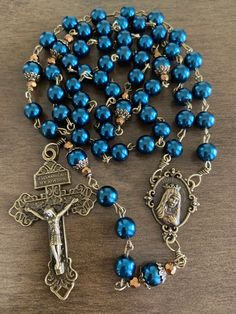 "This beautiful handmade rosary is made with 8mm blue glass pearls, bronze beads cap and 2\" Pardon crucifix. Length: 20\" inches long" Adjustable Blue Rosary With Miraculous Medal, Blue Rosary With 8mm Beads And Crucifix, Blue Rosary With 8mm Beads In Cross Shape, Paracord Rosary, Handmade Rosary, Immaculate Heart Of Mary, Heart Of Mary, Immaculate Heart, Holy Rosary