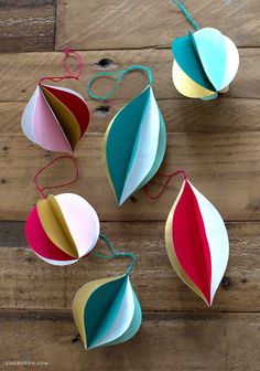 several colorful paper umbrellas hanging from strings on a wooden floor with string attached to them