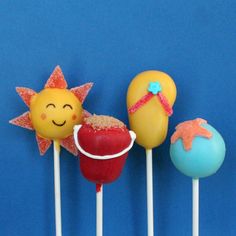 three cake pops with different designs on them and one has a starfish, the other is a sun